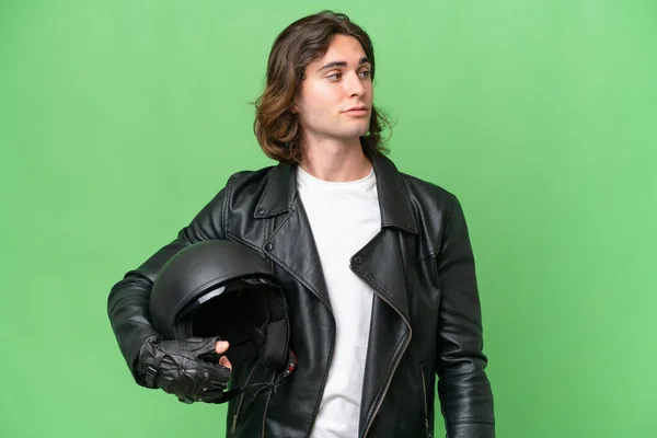 年轻英俊男子 头戴摩托车头盔 背景为绿色 侧面朝外看 — 图库照片