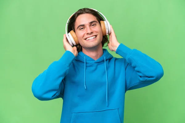 Jovem Bonito Homem Isolado Verde Croma Fundo Ouvir Música — Fotografia de Stock