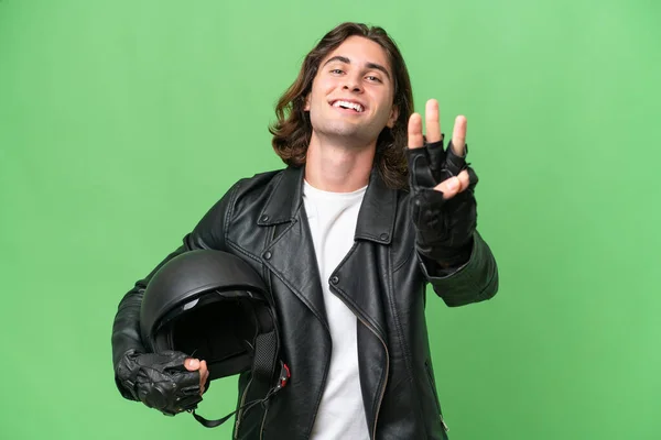 若いですハンサムな男とともにオートバイヘルメット隔離上の緑色の背景幸せとカウント3とともに指 — ストック写真
