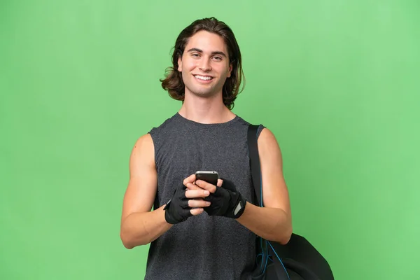 年轻的运动帅哥孤立在绿色的背景下 用手机传递信息 — 图库照片