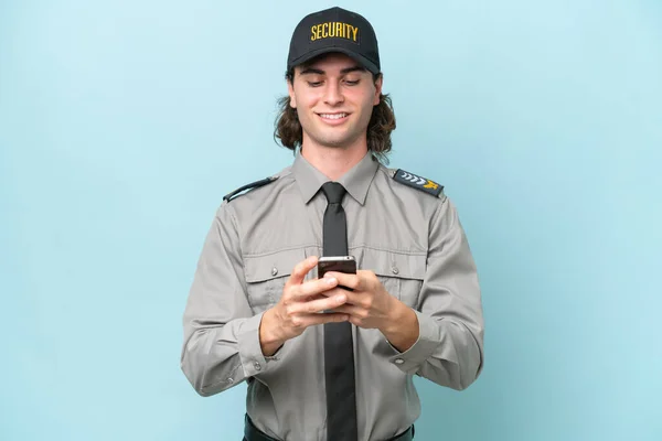 Mladý Ochranka Muž Izolovaný Modrém Pozadí Posílání Zprávy Mobilním — Stock fotografie
