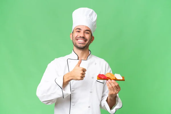 Jeune Chef Caucasien Tenant Sushi Sur Fond Isolé Donnant Pouce — Photo