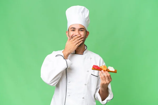 Junger Kaukasischer Koch Hält Ein Sushi Über Isoliertem Hintergrund Glücklich — Stockfoto