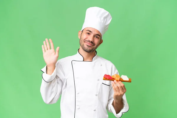Młody Kaukaski Kucharz Trzymając Sushi Odosobnionym Tle Salutując Ręki Szczęśliwy — Zdjęcie stockowe