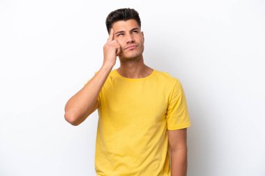 Beyaz arka planda izole edilmiş genç beyaz bir adam deliliğin hareketini yapıyor. Parmağını kafaya koyuyor.