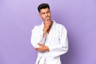 Mor arka planda karate yapan genç beyaz adamın şüpheleri ve düşünceleri var.