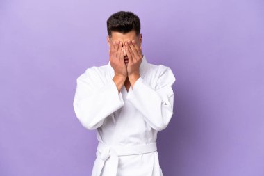 Young caucasian man doing karate isolated on purple background with tired and sick expression