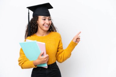 Arap üniversitesinden mezun bir kadın, elinde beyaz arka planda izole edilmiş kitaplar tutarak bir ürünü işaret ediyor.
