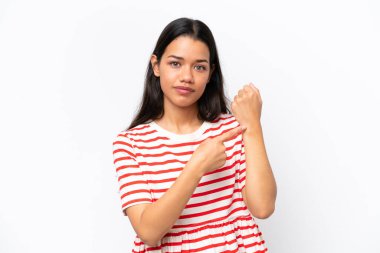 Beyaz arka planda izole edilmiş genç Kolombiyalı kadın geç kalma jesti yapıyor.