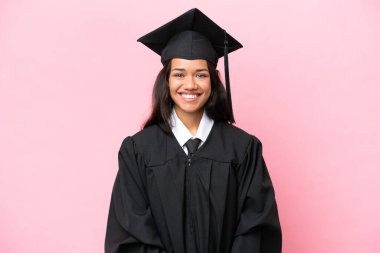 Kolombiyalı genç bir üniversite mezunu pembe arka planda tek başına gülüyor.