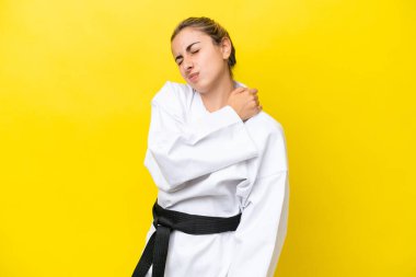 Karate yapan beyaz bir kadın sarı arka planda izole edilmiş, omuz ağrısından muzdarip, çabaladığı için.