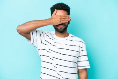 Genç Brezilyalı adam mavi arka planda tek başına, gözleri elle kapatıyor. Bir şey görmek istemiyorum.