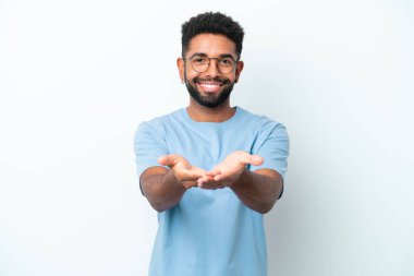 Beyaz arka planda izole edilmiş genç Brezilyalı bir adam bir ilan vermek için avucunun içinde hayali bir mekan tutuyor.