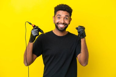 Dövmeli adam Brezilyalı izole edilmiş sarı arka planda galibiyeti kutluyor.