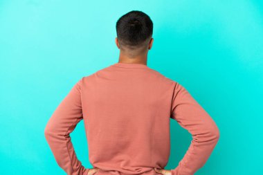 Young handsome man over isolated blue background in back position
