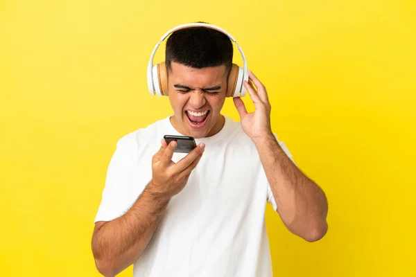 Νεαρός Όμορφος Άντρας Πάνω Από Απομονωμένο Κίτρινο Φόντο Ακούγοντας Μουσική — Φωτογραφία Αρχείου