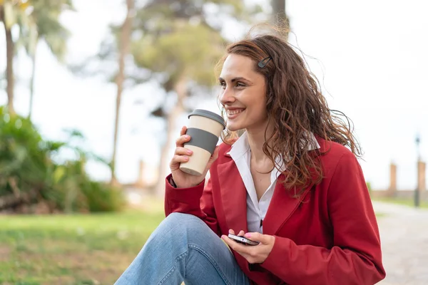 年轻的高加索女人在户外用手机拿着咖啡 — 图库照片
