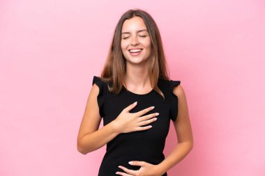 Pembe arka planda izole edilmiş genç beyaz kadın çok gülümsüyor.