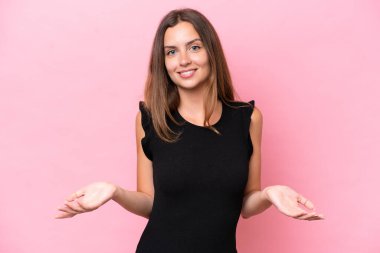 Pembe arka planda izole edilmiş genç beyaz kadın mutlu ve gülümsüyor.