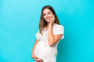 Young caucasian woman isolated on blue background pregnant and happy