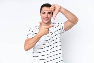 Young caucasian man isolated on white background focusing face. Framing symbol