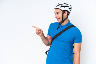 Beyaz arka planda izole edilmiş termal sırt çantalı beyaz tenli genç beyaz bir adam parmak göstererek bir ürün sunuyor.