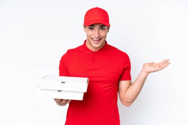 Pizza teslimatı beyaz arka planda izole edilmiş pizza kutularını alan iş üniformalı beyaz bir adam, şok olmuş bir yüz ifadesi var.