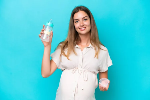 Young Caucasian Woman Isolated Blue Background Pregnant Holding Feeding Bottle — Stock fotografie