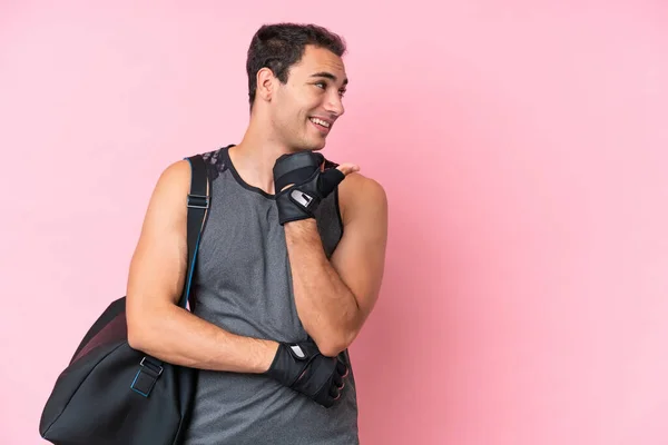 stock image Young sport caucasian man with sport bag isolated on pink background pointing to the side to present a product