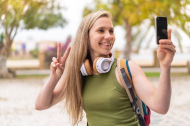 Açık havada selfie çeken genç sarışın kadın.