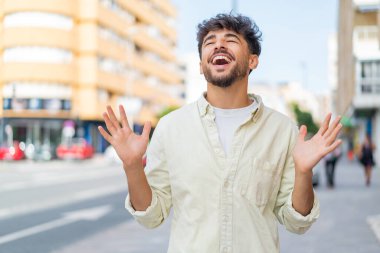 Açık havada gülümseyen yakışıklı genç bir Arap.