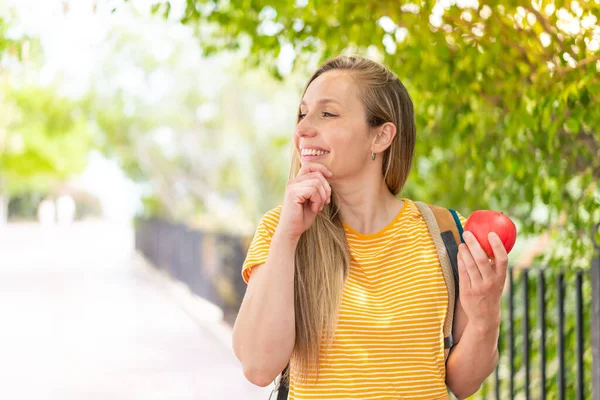 Mujer Rubia Joven Con Una Manzana Aire Libre Pensando Una —  Fotos de Stock