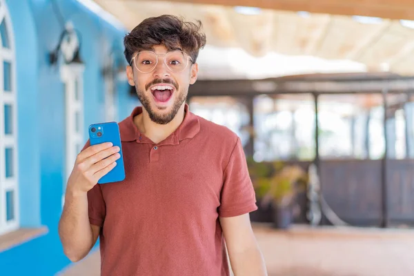 Mladý Arabský Pohledný Muž Používající Mobilní Telefon Venku Překvapením Šokovaným — Stock fotografie