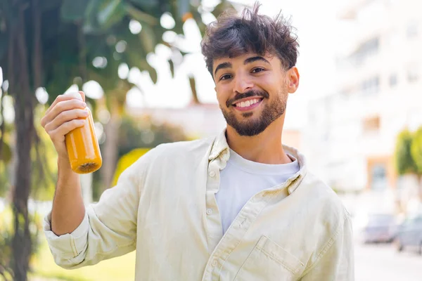 Mladý Arabský Pohledný Muž Drží Pomerančový Džus Venku — Stock fotografie