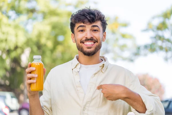 Mladý Arabský Pohledný Muž Drží Pomerančovou Šťávu Venku Překvapením Výraz — Stock fotografie