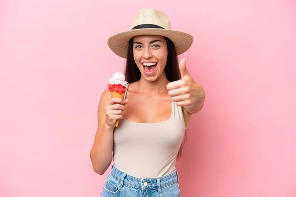 年轻的高加索女人 带着玉米粒冰淇淋 背景是粉红色的 大姆指向上 因为发生了一些好事 — 图库照片