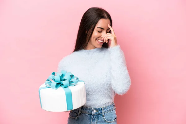 stock image Young caucasian woman holding birthday cake isolated on pink background laughing