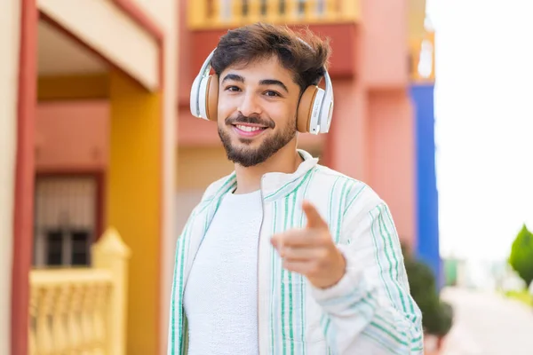 Hombre Árabe Guapo Aire Libre Escuchando Música Señalando Hacia Frente —  Fotos de Stock