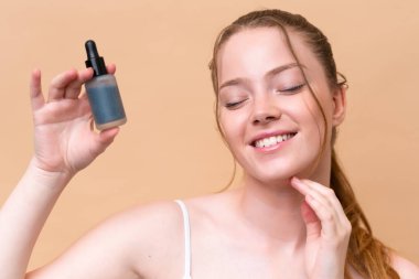 Beyazlı genç bir kız bej arka planda izole edilmiş ve elinde serum var. Portreyi kapat