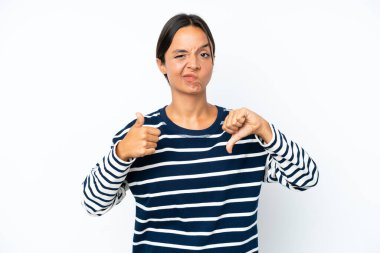 Beyaz arka planda izole edilmiş genç İspanyol kadın iyiye-kötüye işaret veriyor. Evet ya da hayır arasında kararsız