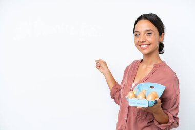 Beyaz arka planda izole edilmiş yumurtaları tutan genç İspanyol kadın.