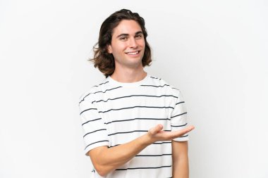 Beyaz arka planda soyutlanmış genç yakışıklı bir fikir sunuyor ve gülümsüyor.