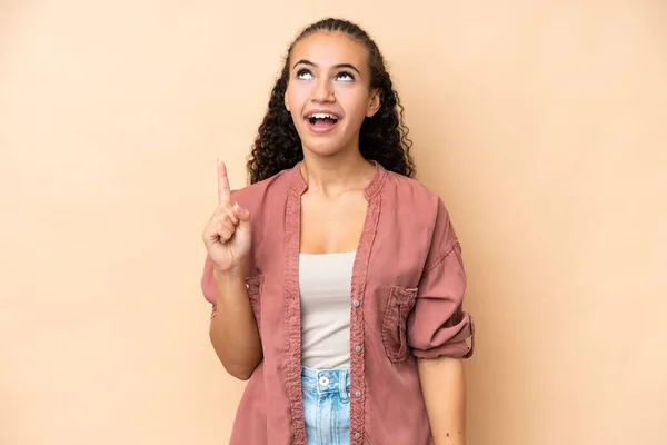 stock image Young woman isolated on beige background pointing up and surprised