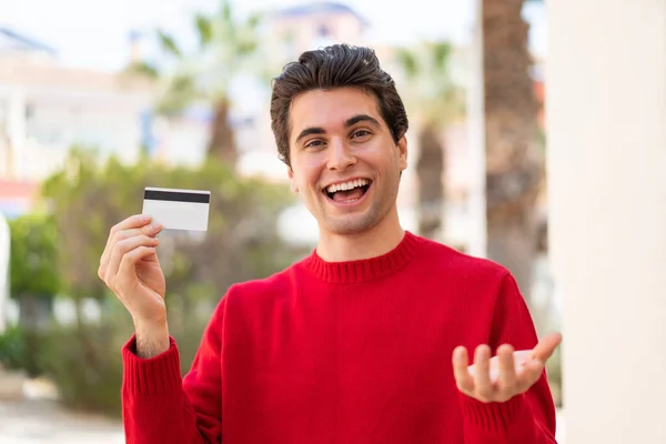 Young Handsome Man Holding Credit Card Outdoors Shocked Facial Expression — Stock Photo, Image
