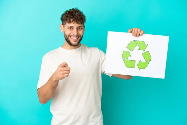 Mladý Pohledný Běloch Izolovaný Modrém Pozadí Drží Plakát Ikonou Recyklace — Stock fotografie