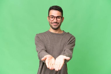 İzole edilmiş arka plan üzerinde yakışıklı beyaz bir adam bir ilan vermek için fotokopi makinesini avucunun içinde tutuyor.