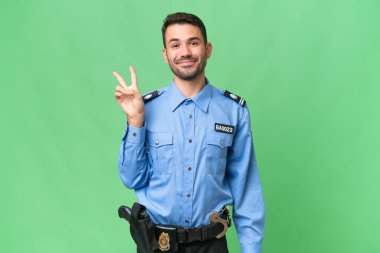 Genç polis beyaz adam izole edilmiş arka planda gülümsüyor ve zafer işareti gösteriyor.