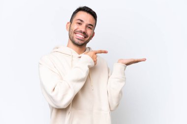 Beyaz arka planda izole edilmiş genç beyaz bir adam bir ilan vermek için avucunun içinde hayali bir fotokopi makinesi tutuyor.