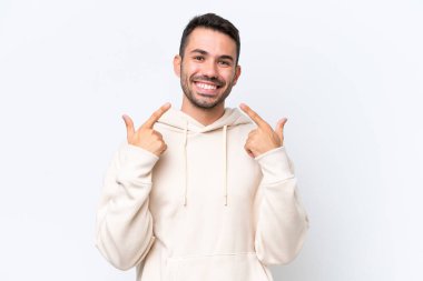 Beyaz arka planda izole edilmiş genç beyaz bir adam baş parmak hareketi yapıyor.