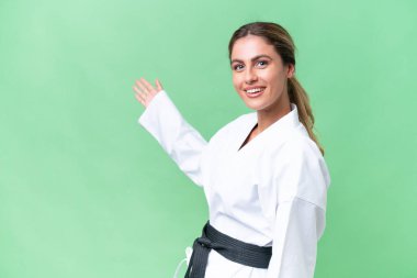 Genç Uruguaylı kadın izole edilmiş arka planda karate yapıyor. Davet etmek için ellerini yana uzatıyor.